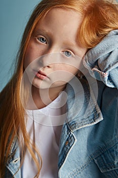 Young red-haired girl with long beautiful hair and big blue eyes. Hair the color of fire fluttering in the wind. Girl child with a