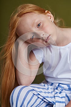 Young red-haired girl with long beautiful hair and big blue eyes. Hair the color of fire fluttering in the wind. Girl child with a