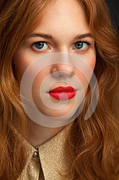 Young red-haired girl looks at the camera. Portrait of a young woman