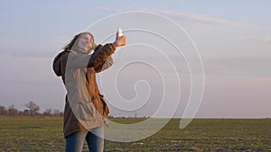Young red-haired girl makes a selfie with a smartphone camera during wind