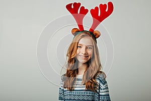 A young red-haired girl smiles and looks at the camera before Christmas. She is preparing for the celebration of the new