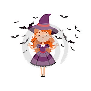 Young red-haired girl witch standing with hands up and wearing purple dress and hat. Kid character in Halloween costume