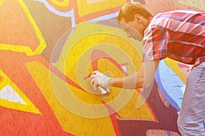 A young red-haired graffiti artist paints a new graffiti on the