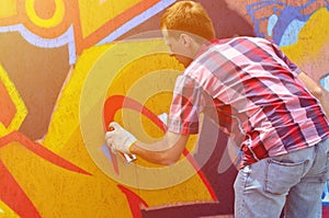 A young red-haired graffiti artist paints a new graffiti on the