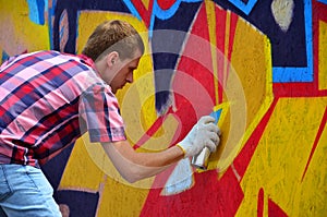 A young red-haired graffiti artist paints a new graffiti on the wall