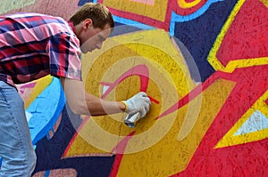 A young red-haired graffiti artist paints a new graffiti on the wall