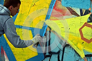 A young red-haired graffiti artist paints a new graffiti on the wall