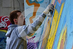 A young red-haired graffiti artist paints a new graffiti on the wall