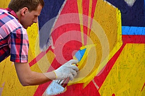 A young red-haired graffiti artist paints a new graffiti on the wall