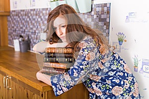 Young red-haired woman relaxing at home with books. Quarantine, isolation, coronavirus pandemic world. Stay at home.