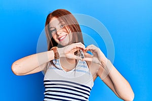 Young red head girl wearing casual clothes smiling in love doing heart symbol shape with hands