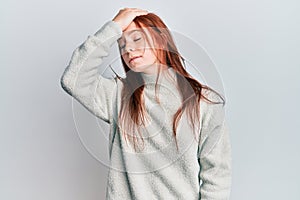 Young red head girl wearing casual winter sweater surprised with hand on head for mistake, remember error