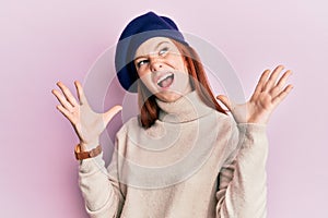 Young red head girl wearing french look with beret crazy and mad shouting and yelling with aggressive expression and arms raised
