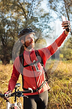 Young red-headed man taking a selfie while riding mountain bike in beautiful late summer afternoon