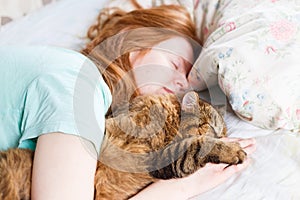 Young redhair woman sleeping with cat photo