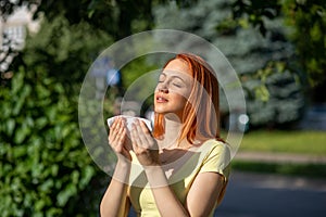 Young redhair woman sneezing in park. Pollen Allergy symptoms photo