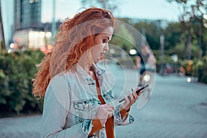 Young redhaired woman  standing at night with phone