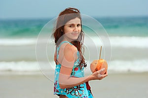 Young redhead on the beach with a coconut
