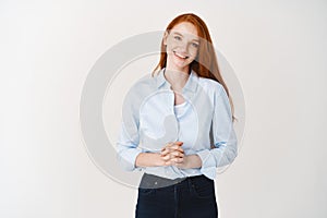 Young redhead business woman looking like professional, smiling friendly, listening client, standing over white