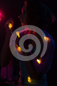 Young redhead Caucasian woman holding fairy lights portrait red background light