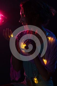 Young redhead Caucasian woman holding fairy lights portrait red background light