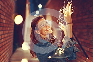 Young redhead woman playing with fairy lights outdoors toothy smile photo