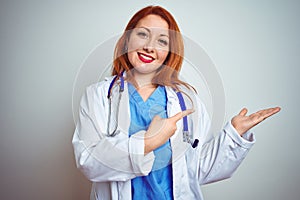 Young redhead doctor woman using stethoscope over white isolated background amazed and smiling to the camera while presenting with