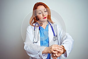 Young redhead doctor woman using stethoscope over white isolated background Checking the time on wrist watch, relaxed and