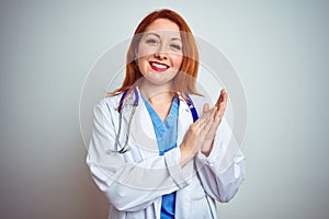 Young redhead doctor woman using stethoscope over white isolated background clapping and applauding happy and joyful, smiling