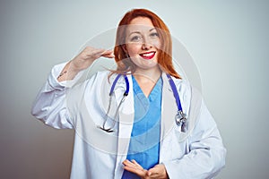 Young redhead doctor woman using stethoscope over white isolated background gesturing with hands showing big and large size sign,