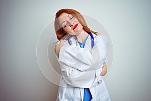 Young redhead doctor woman using stethoscope over white isolated background Hugging oneself happy and positive, smiling confident