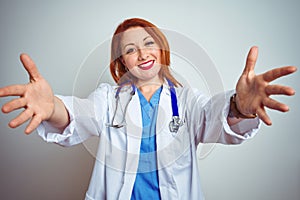 Young redhead doctor woman using stethoscope over white isolated background looking at the camera smiling with open arms for hug