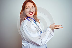 Young redhead doctor woman using stethoscope over white isolated background pointing aside with hands open palms showing copy