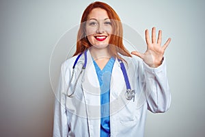 Young redhead doctor woman using stethoscope over white isolated background showing and pointing up with fingers number five while