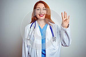 Young redhead doctor woman using stethoscope over white isolated background showing and pointing up with fingers number four while