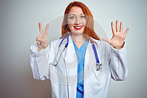 Young redhead doctor woman using stethoscope over white isolated background showing and pointing up with fingers number seven