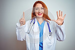 Young redhead doctor woman using stethoscope over white isolated background showing and pointing up with fingers number six while