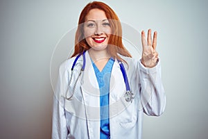 Young redhead doctor woman using stethoscope over white isolated background showing and pointing up with fingers number three