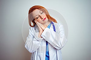 Young redhead doctor woman using stethoscope over white isolated background sleeping tired dreaming and posing with hands together