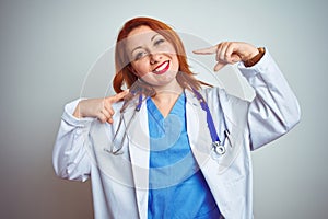 Young redhead doctor woman using stethoscope over white isolated background smiling cheerful showing and pointing with fingers