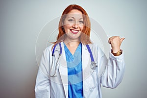 Young redhead doctor woman using stethoscope over white isolated background smiling with happy face looking and pointing to the