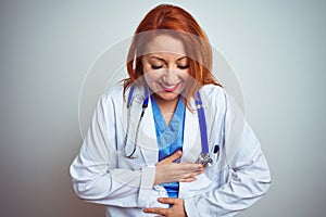 Young redhead doctor woman using stethoscope over white isolated background smiling and laughing hard out loud because funny crazy