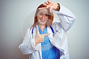 Young redhead doctor woman using stethoscope over white isolated background smiling making frame with hands and fingers with happy