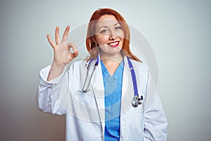 Young redhead doctor woman using stethoscope over white isolated background smiling positive doing ok sign with hand and fingers