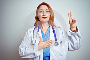 Young redhead doctor woman using stethoscope over white isolated background smiling swearing with hand on chest and fingers up,