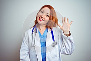 Young redhead doctor woman using stethoscope over white isolated background Waiving saying hello happy and smiling, friendly