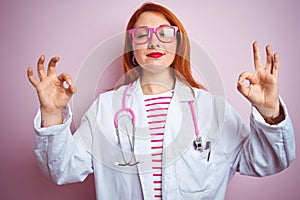 Young redhead doctor woman using stethoscope standing over isolated pink background relax and smiling with eyes closed doing