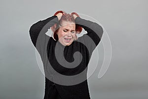 Young fat lady in black sweater upset woman crying, pining holding hands in hair photo