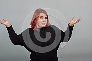 Young redhead fat lady in black sweater woman doubts decision, spreads arms wide