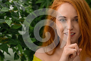 Young redhead girl asking to keep silence photo